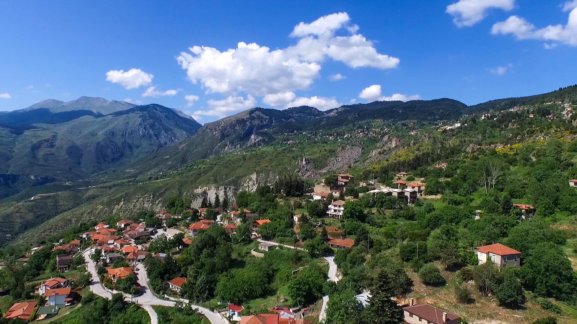 Trikala Korinthias: A Guide to the 3 Districts & Mt. Zireia 1 Panoramic view of Trikala Korinthias: tile-roofed houses on a green slope with the Ziria mountains behind